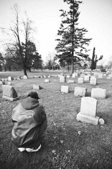 Joseph Thomas Jr. kneels in front of his son's grave