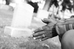 Joseph Thomas Sr.'s hands, close up, as he kneels at Forest Lawn Cemetery