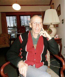 Larry Cohen, wearing a red-and-black sweater and glasses, with a shaved head